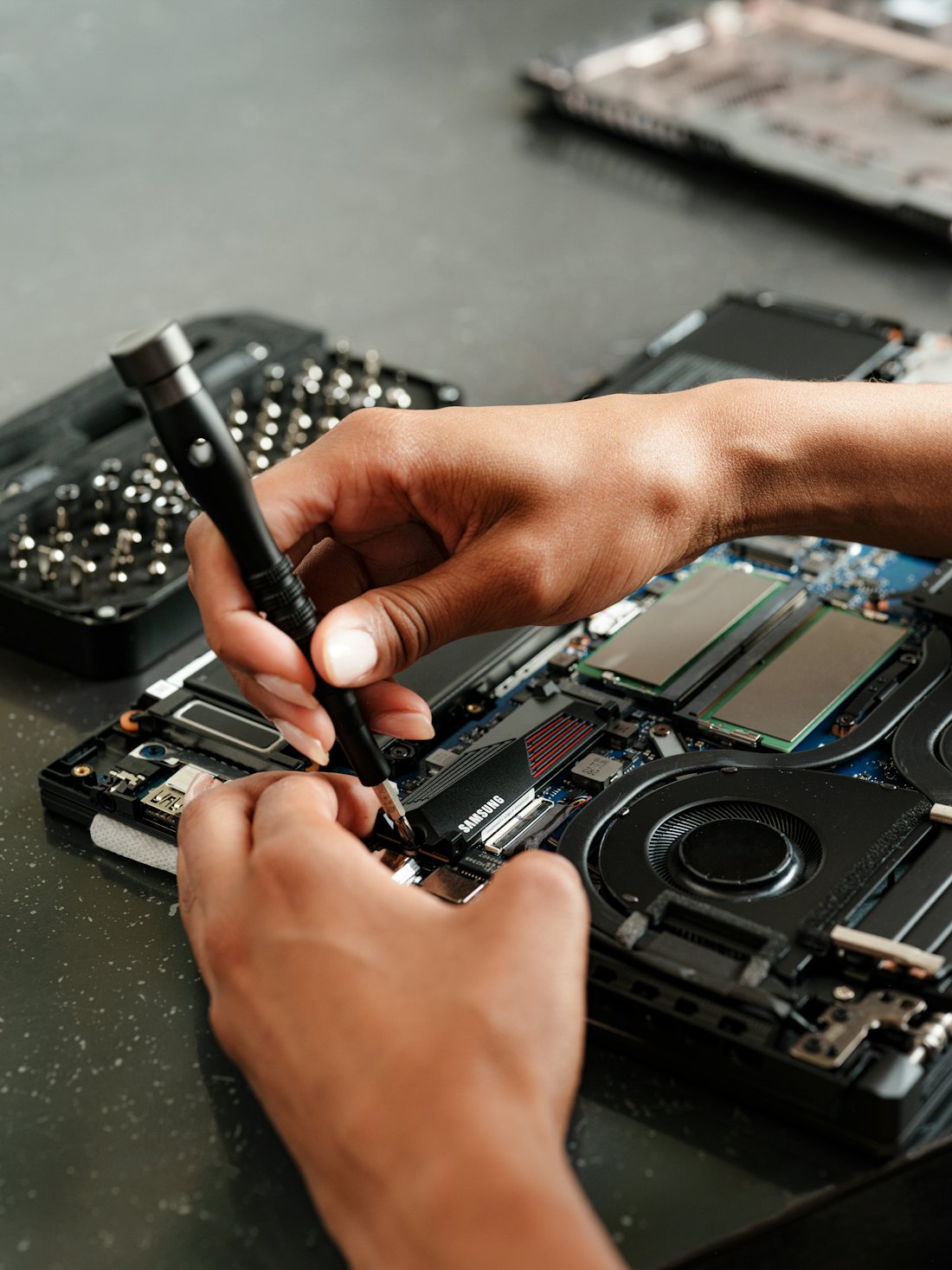Mains qui dévissent un PC portable ouvert