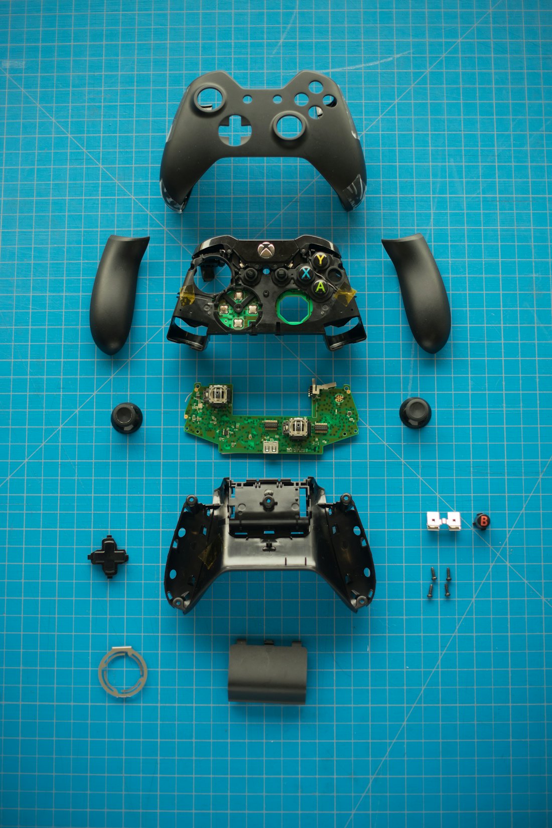 Manette Xbox démontée, pièces posées sur un tapis de travail